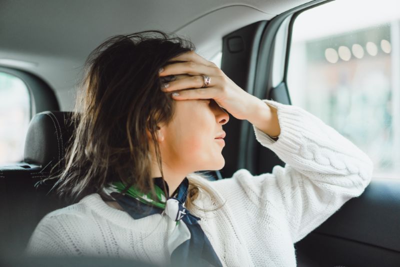 woman in the back seat of a car with her head in her hands