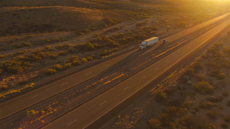 Aerial view of a semi truck driving on the highway during sunset