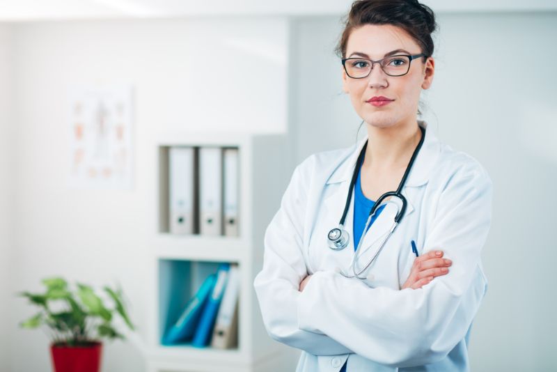 Female doctor standing in office with her arms crossed