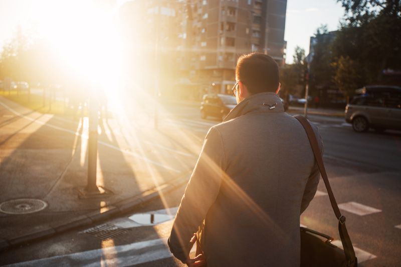 Man crossing a crosswalk in the evening with lens glare