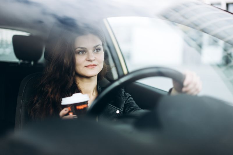 Woman driving with a cup of coffee in one hand