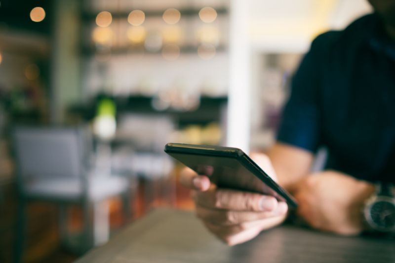 Scrolling on cell phone in a public cafe