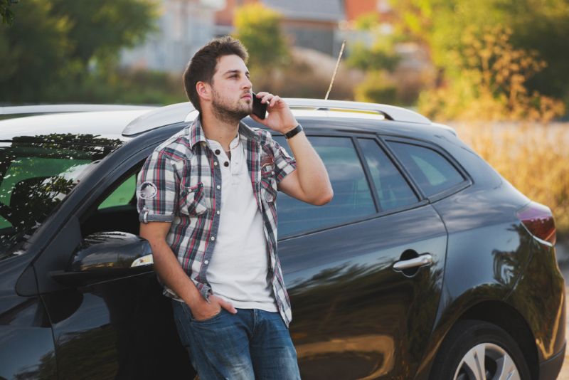 Man taking a phone call outside of his car